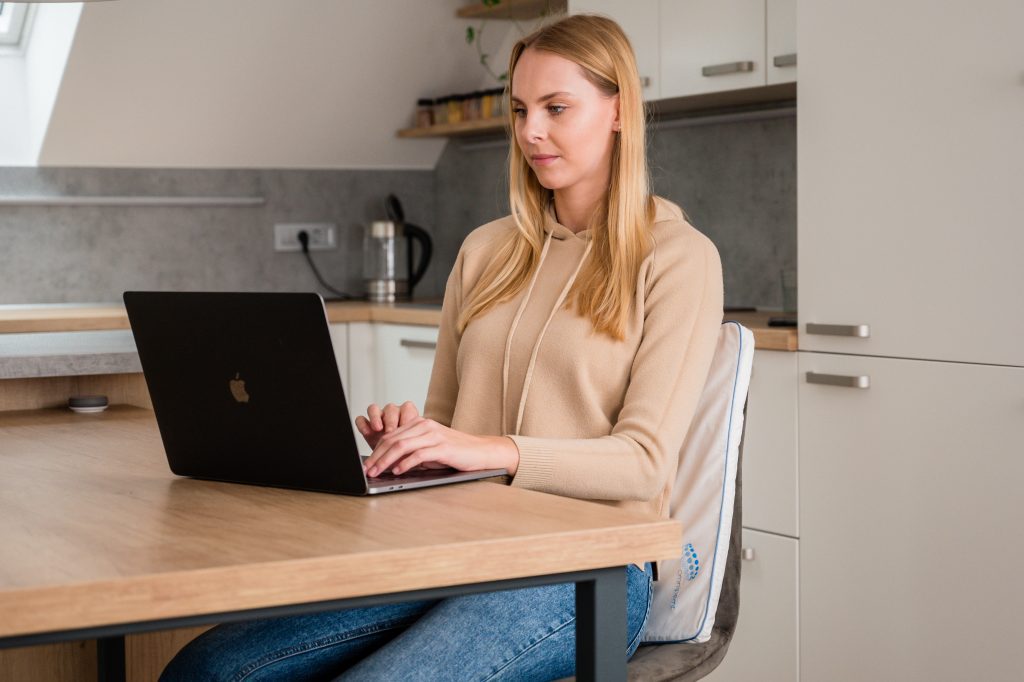 Femeie la laptop in bucatarie folosind Perna Omnipemf Cotton